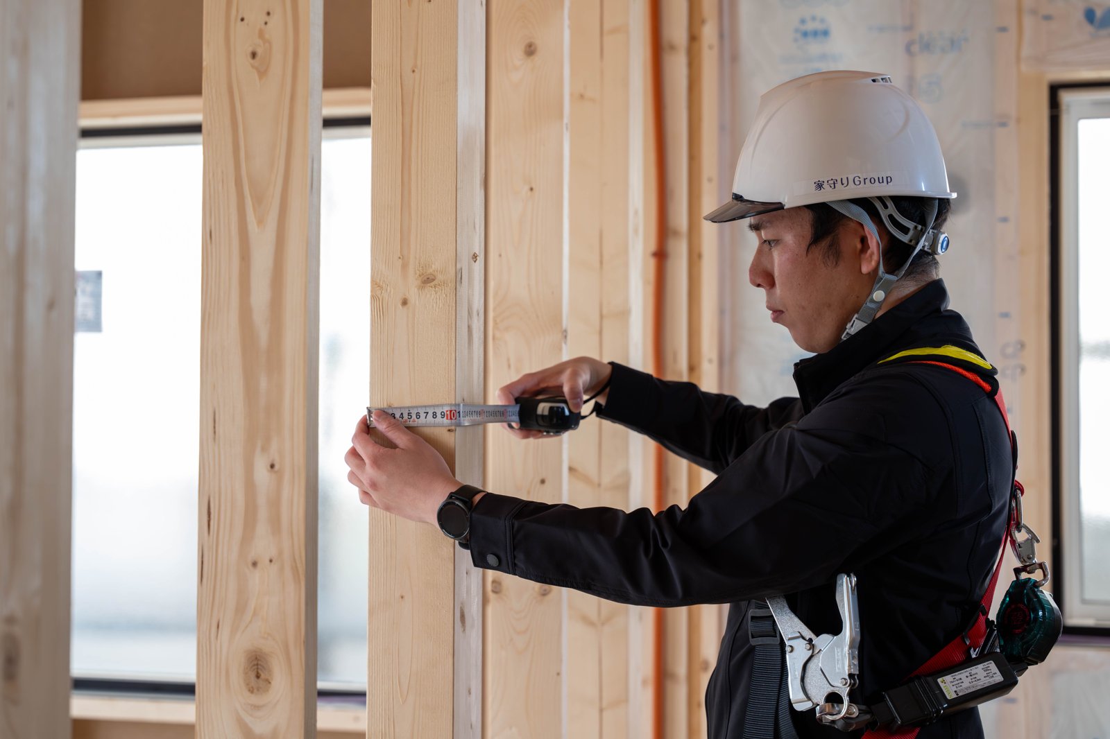 家守りの検査員が、工事中の住宅でメジャーを当てて寸法を確認している様子（写真提供：家守り）